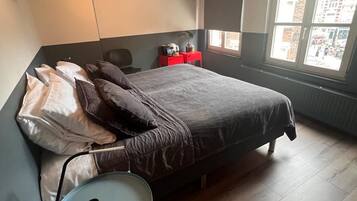 A bedroom with a bed, a small table, and a chair.