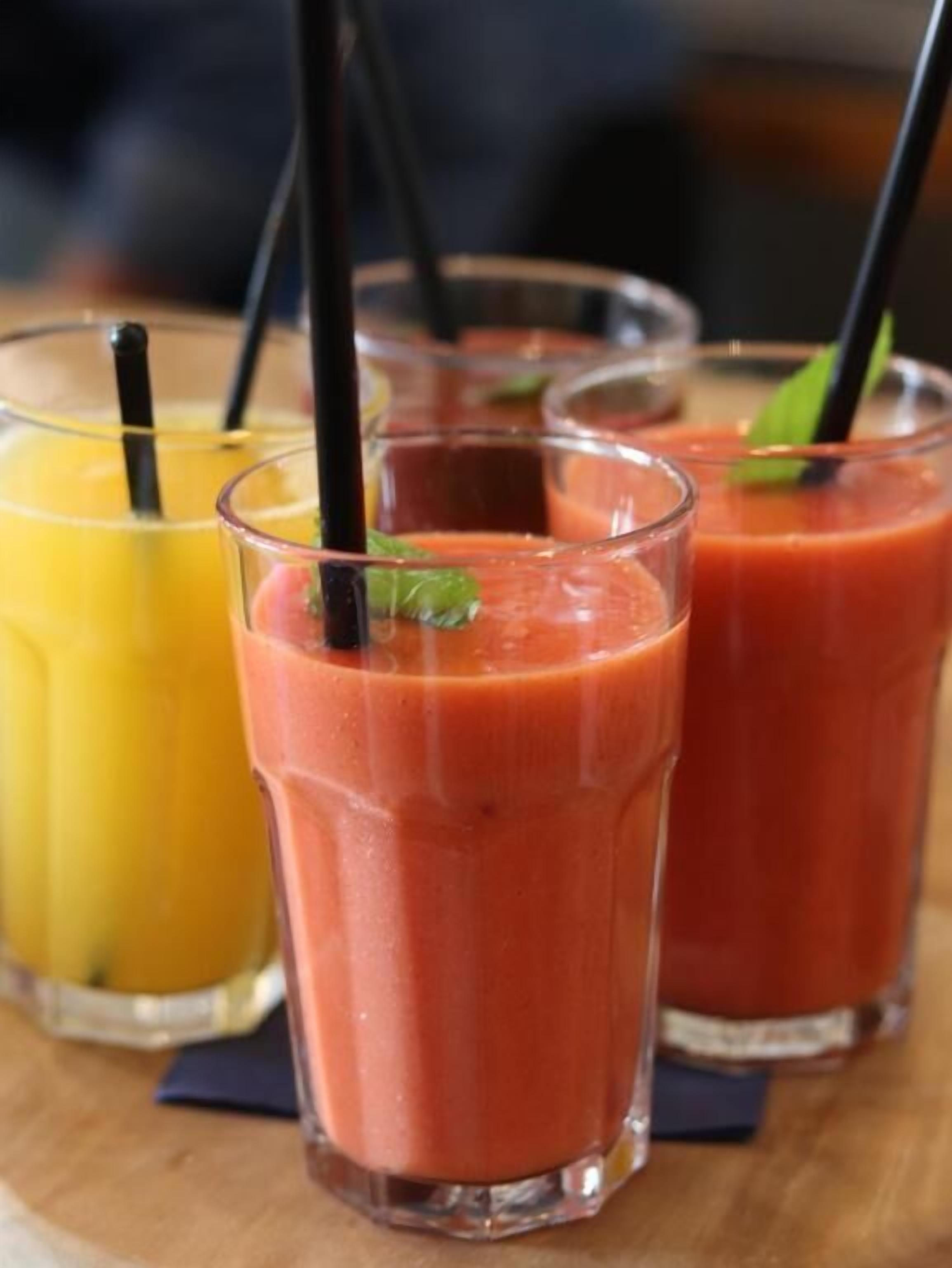Três copos de smoothie sobre uma mesa de madeira.