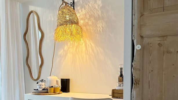 A cozy workspace with a white desk, a woven lamp, and a white chair. - Milk and Cookies (Venlo)