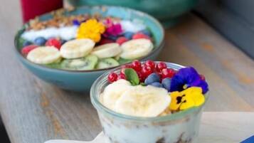 A bowl of yogurt with fruits and granola, a glass of yogurt with fruits, and a decorative candle holder.