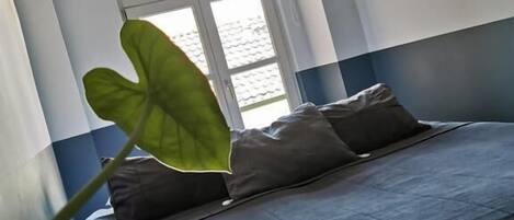 A room with a bed, a window, and a plant.