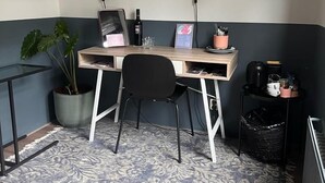 A small, neatly organized workspace with a desk, two chairs, a potted plant, and a coffee machine. - Milk and Cookies (Venlo)