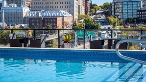 Une piscine sur le toit offrant une vue sur la ville, avec des bâtiments et une route visibles.