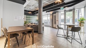 Un espacio de oficina moderno con una amplia mesa de reuniones, asientos cómodos y grandes ventanales con vistas a la calle.