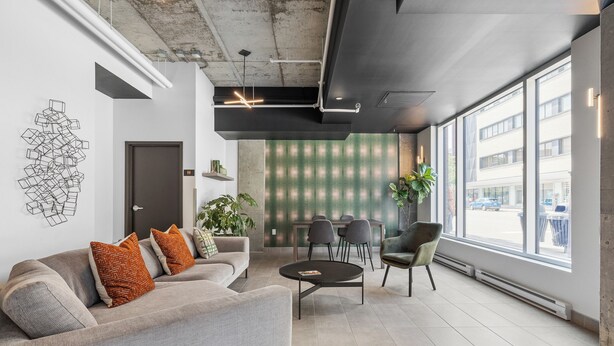A modern office space with a grey sofa, a round table, and a large window offering a view of the street. - The Caïman Complex, 608 + parking (Québec City)