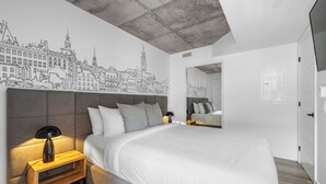 A modern bedroom with a cityscape mural, a large bed, bedside tables, and a wooden bench. - The Caïman Complex, 404, The Caïman - 404 - Terrace + Pool (Québec City)