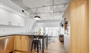 Una cocina moderna con armarios de madera, lavavajillas de acero inoxidable y un comedor con mesa y sillas.