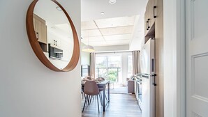 Eine moderne Küche mit Holzausstattung, ein Essbereich mit Tisch und Stühlen sowie ein großes Fenster mit Blick auf die Stadt.