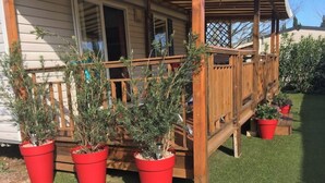 Ett trädäck med röda blomlådor och ett hus i bakgrunden.
