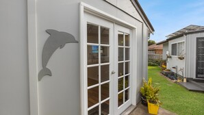 Una casa con fachada blanca, un amplio ventanal corredero y un recorte en la pared con forma de delfín.