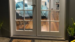 Puertas dobles con paneles de vidrio esmerilado que dan paso a una habitación con cama y escritorio.
