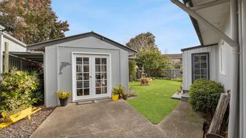 Enjoy a serene suburban setting surrounded by mature trees and a beautifully maintained yard with potted plants.