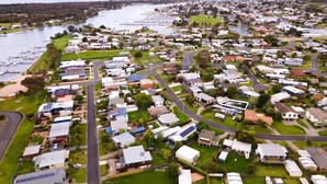Vista aérea de una zona residencial con casas, calles y un puerto deportivo con barcos.