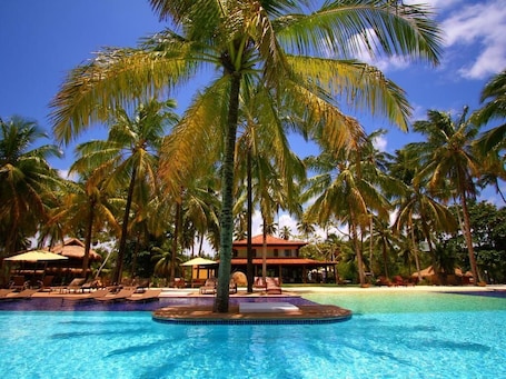 Una piscina al aire libre, sombrillas, sillones reclinables de piscina