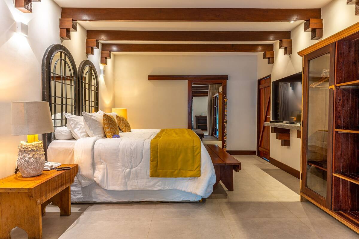 Une chambre à coucher avec un lit, des tables de chevet, un miroir et une armoire.