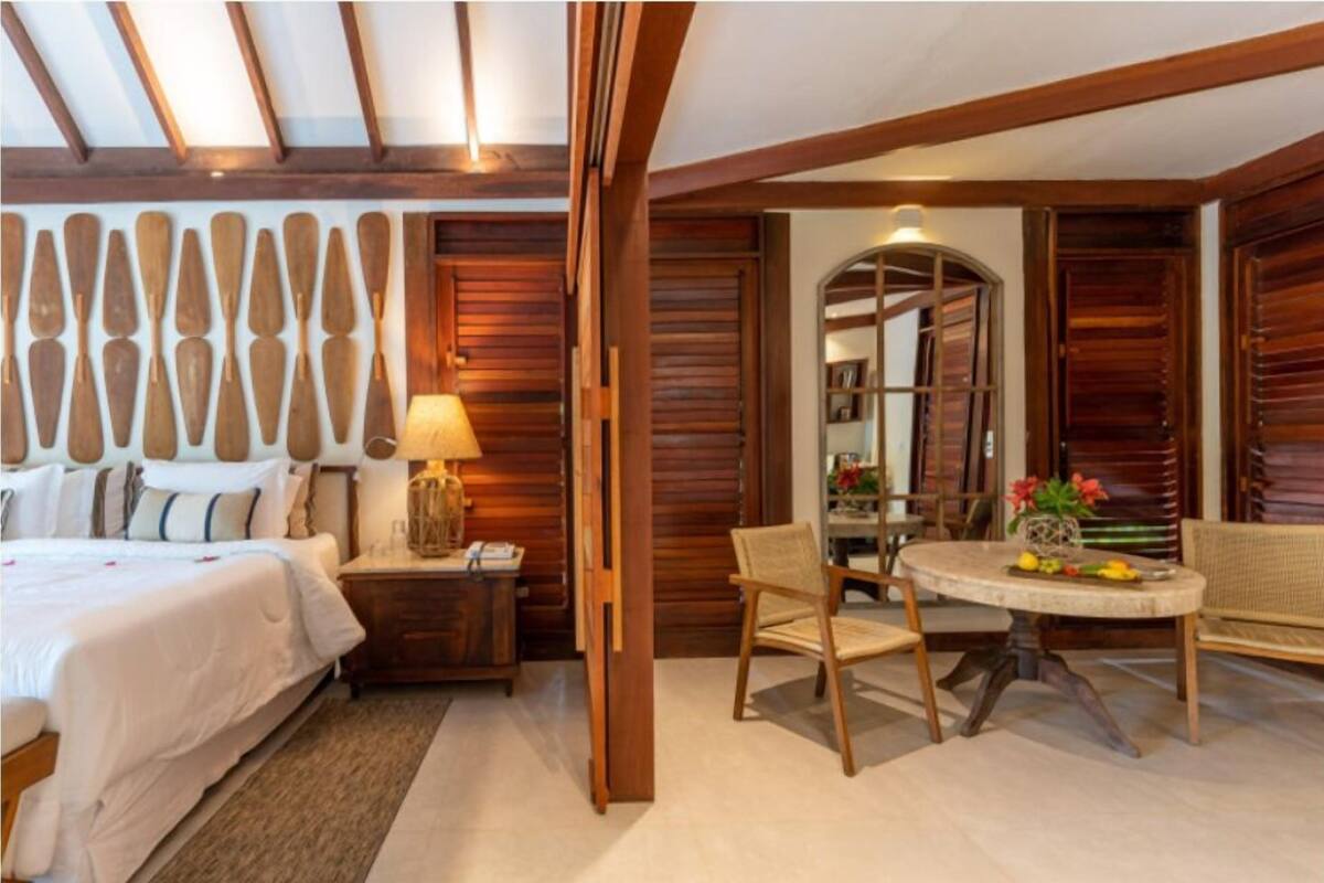 Une chambre d’hôtel comprenant un lit, une table de chevet, une table avec des chaises et un panneau mural en bois.