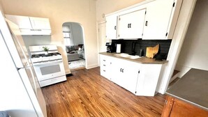 Una cocina moderna con armarios blancos, piso de madera y horno empotrado.