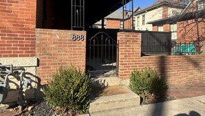 Un edificio de ladrillo con una reja de metal negro y el número '888' en la pared.