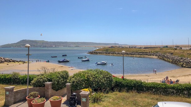 Une vue sur la côte, avec des bateaux sur l’eau, une plage de sable et un ciel dégagé.
