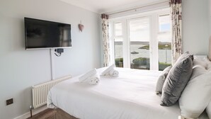 Une chambre dotée d’un grand lit, d’un téléviseur à écran plat fixé au mur, d’une vue sur la mer par la fenêtre et d’un radiateur également fixé au mur.