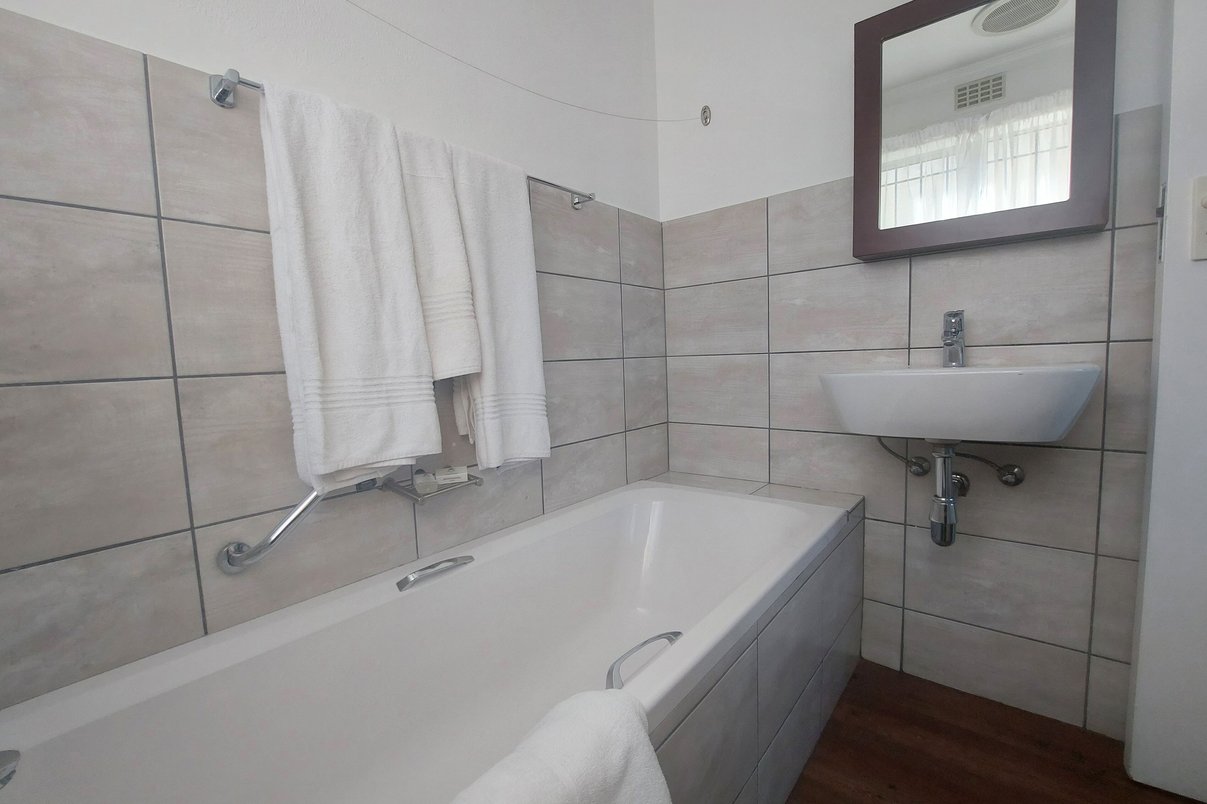 Un baño moderno con bañera, lavabo y espejo.