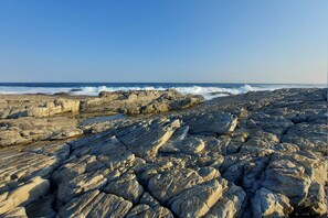 A rocky shoreline with waves crashing against the rocks. - First Group Hermanus Beach Club (Hermanus)
