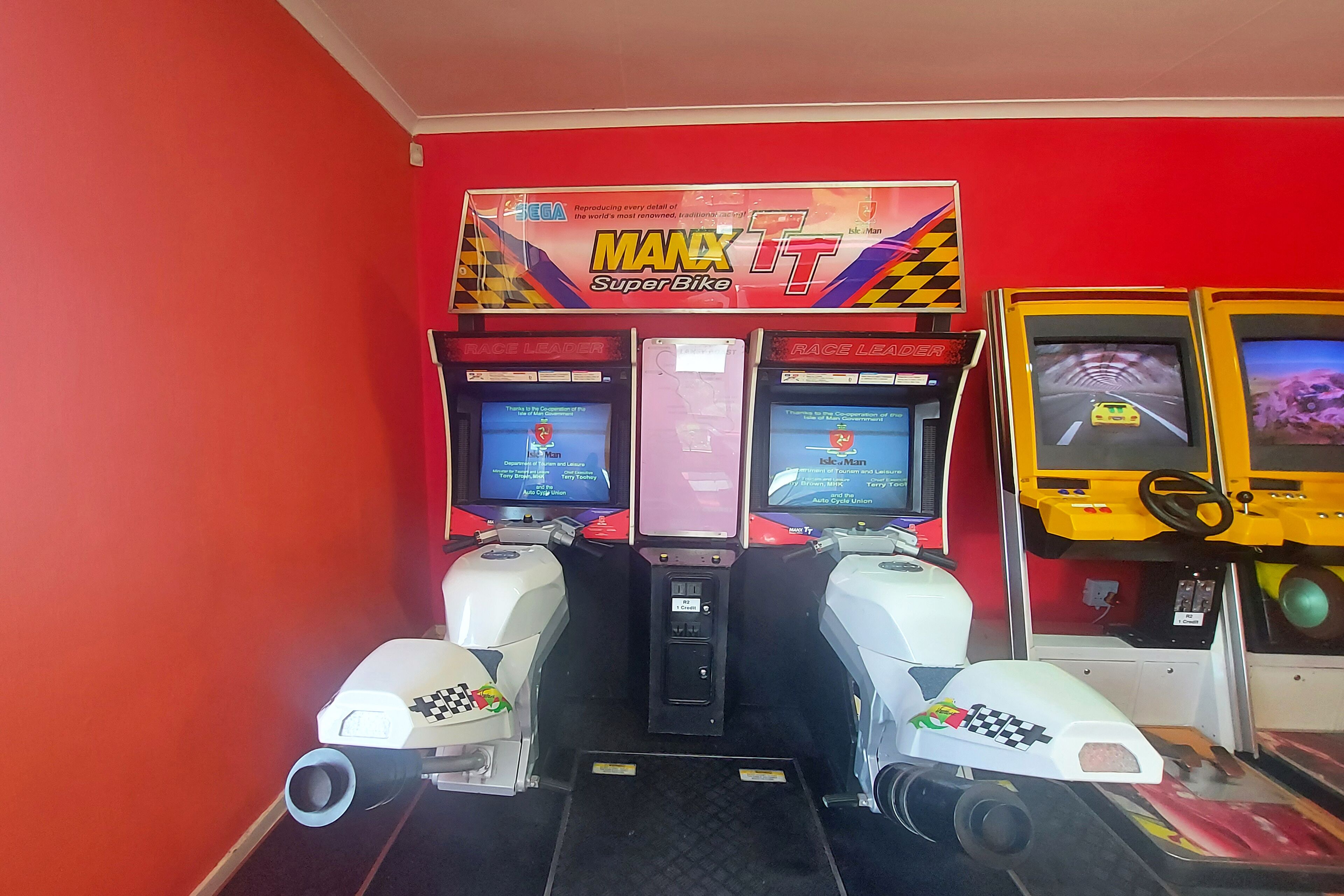 A racing arcade with multiple Sega racing games, including 'Manx TT Super Bike' and 'Raceland'.