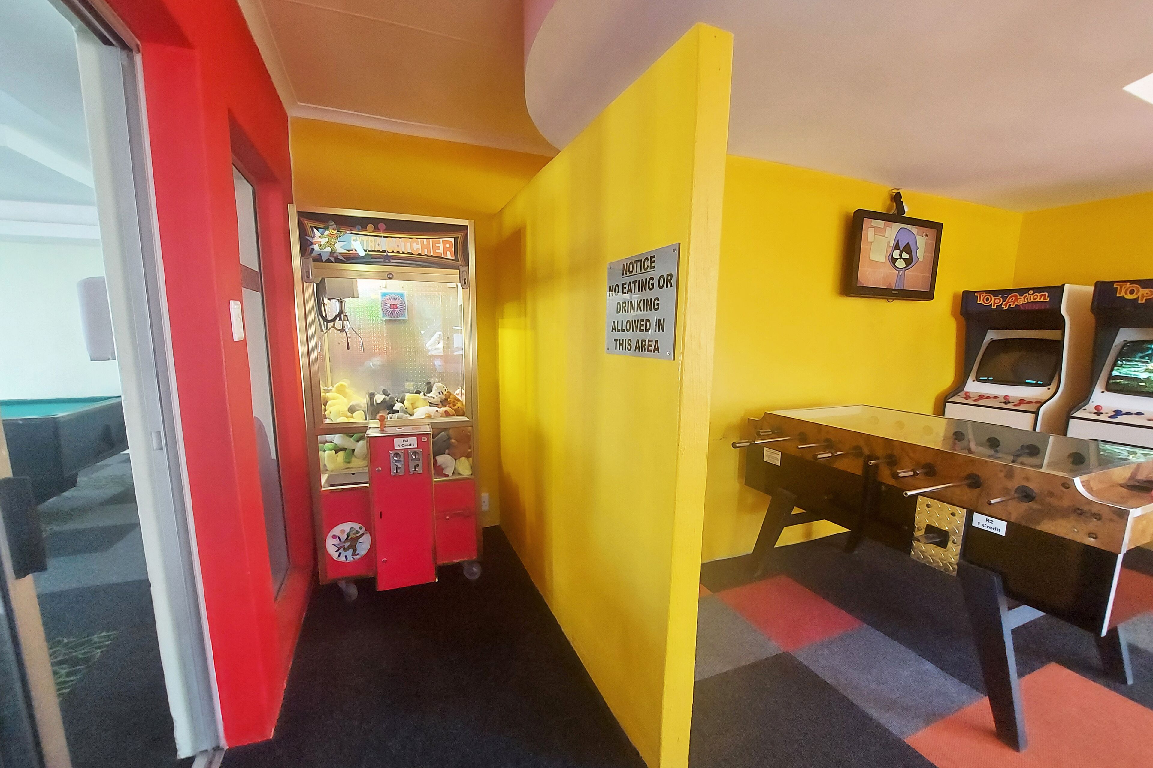 A room with a foosball table, a claw machine, and a notice sign.