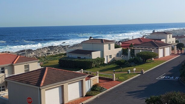 Una zona residencial costera con casas, una señal de stop y el océano al fondo.