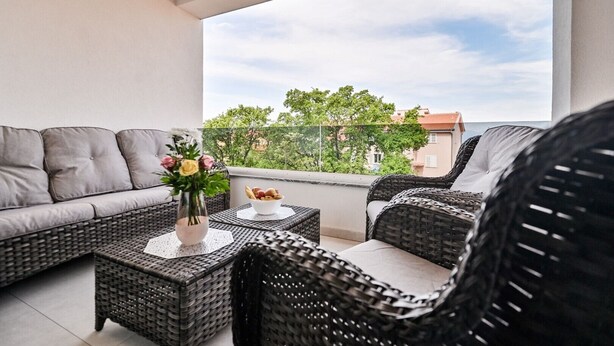 A balcony with wicker furniture, a vase with flowers, and a bowl of bread. - Modern Apartment with balcony and sea view (Milcetici)