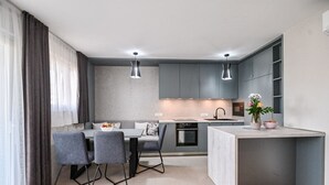 A modern kitchen with grey cabinets, a dining table with chairs, and pendant lights. - Modern Apartment with balcony and sea view (Milcetici)