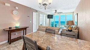 A dining area with a marble table, chairs, a wooden console table, and a chandelier. - Stunning Oceanfront Views w/Pool & Beach Access (Gulf Shores)