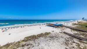 A beach with a pier, beach umbrellas, and a boardwalk. - Stunning Oceanfront Views w/Pool & Beach Access (Gulf Shores)