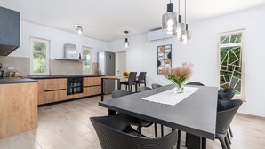 A modern kitchen with wooden cabinets, a central island, and a dining area with a long table and chairs. - Lovely Villa Oliveti with a swimming pool (Frata)
