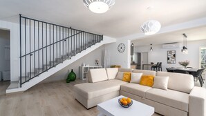 A modern living room with a staircase, a sectional sofa, a dining area, and a kitchen in the background. - Lovely Villa Oliveti with a swimming pool (Frata)