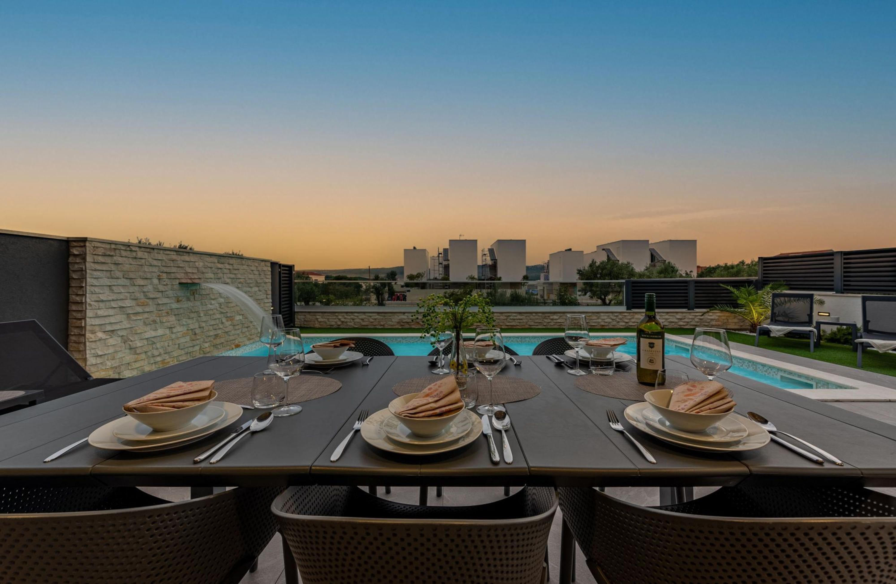 Un espace de restauration aménagé sur le toit, offrant une vue sur la piscine, avec des tables dressées pour le repas, et un panorama urbain en arrière-plan.