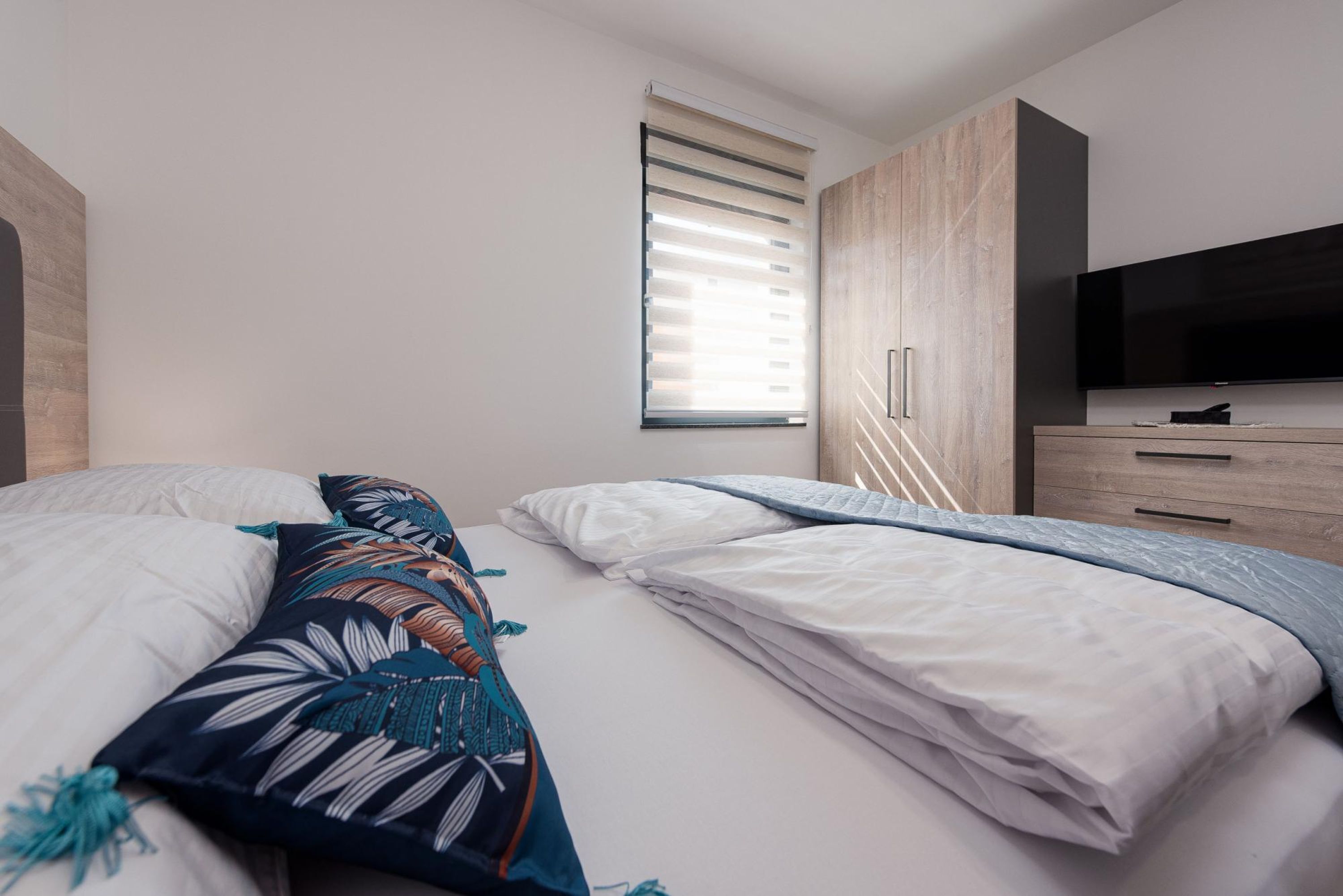 Une chambre à coucher avec un lit, une télévision et une fenêtre équipée de stores.