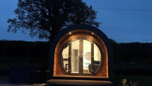 Een ronde houten constructie met een glazen deur en een klein terras.