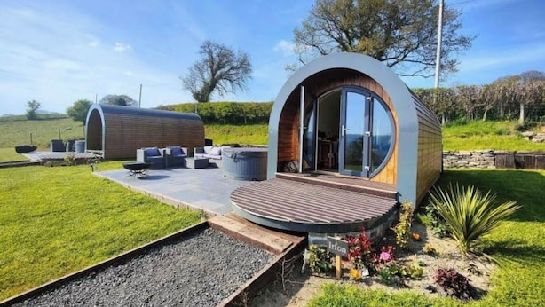 Een modern, rond huis met een houten terras en een zitgedeelte buiten.