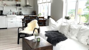 Un salón amplio con un sofá, un cofre de madera y un comedor al fondo.