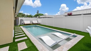 A rectangular swimming pool with a clear blue water surface, surrounded by a white fence and a well-maintained lawn. - Mykonos: Beautifully updated with heated pool, moments to the Gulf (Anna Maria)
