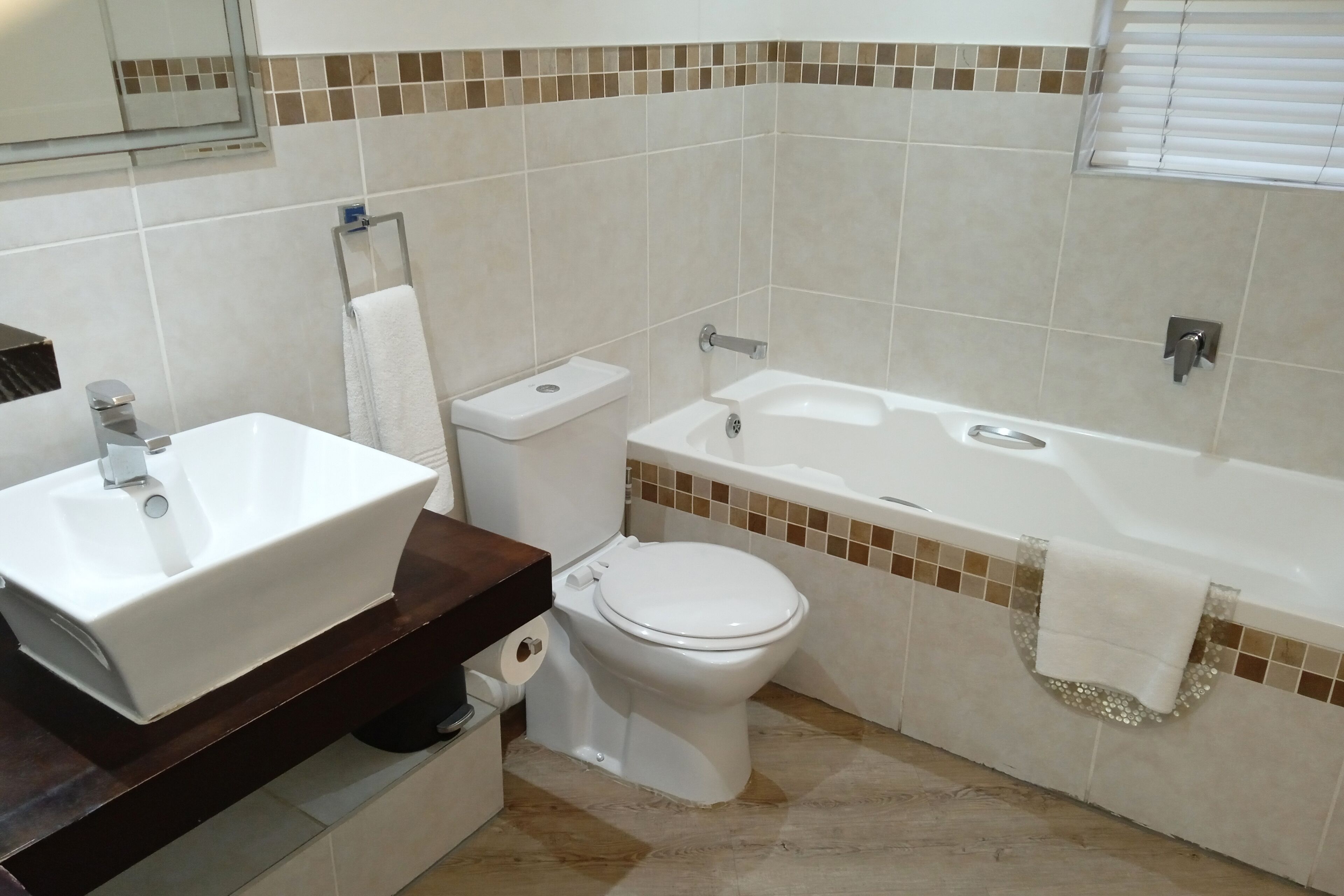 Een badkamer met een wit wastafelmeubel, toilet en bad.