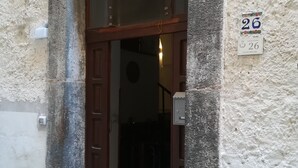 Une entrée d’immeuble avec une porte en bois, une petite fenêtre et une plaque indiquant le numéro de l’immeble.