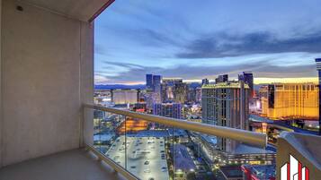 A balcony with a cityscape view, including high-rise buildings and a parking lot.