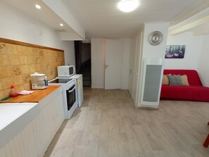 A compact living space with a kitchenette, a red sofa, and a small dining area.