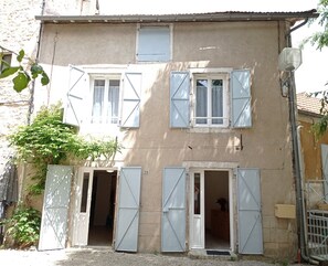 A two-story building with a beige facade, multiple windows with shutters, and a number '28' on the wall.