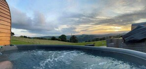 Unwind in a serene hot tub surrounded by lush green landscapes and rolling hills.