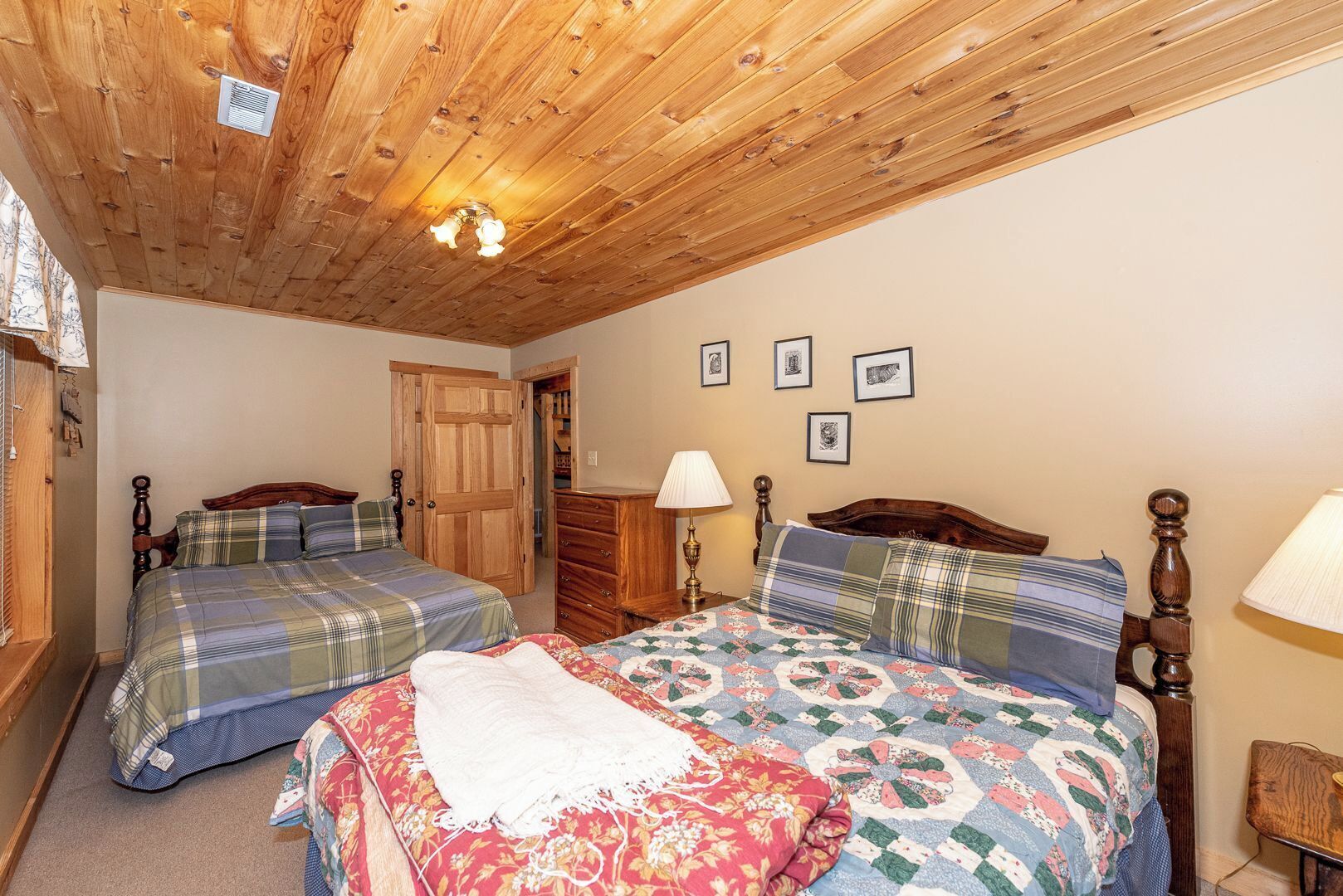 Une chambre avec deux lits, un plafond en bois et une commode.