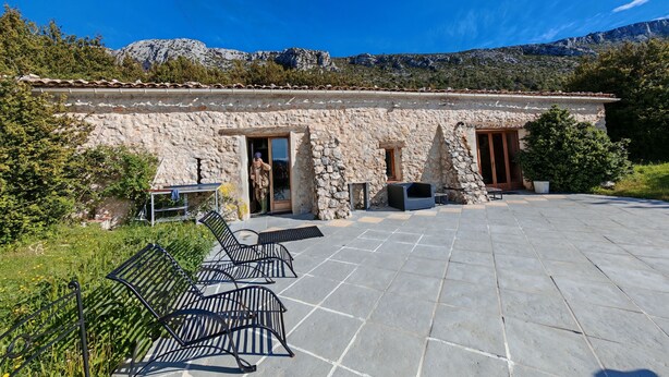 A stone building with a tiled patio, outdoor seating, and a mountainous backdrop. - Very pretty, bright, south-facing sheepfold on an organic farm in the Verdon.  (Var)