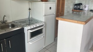 Une cuisine de taille réduite équipée d’une cuisinière à gaz, d’un four et d’un réfrigérateur.